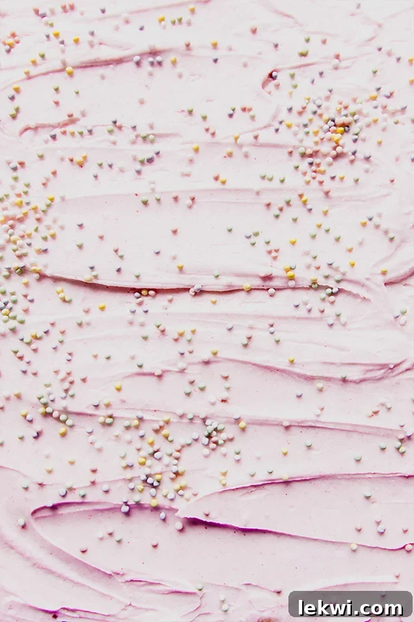 A festive tray of funfetti pink sugar cookie bars, generously adorned with pink icing and colorful sprinkles, ready for sharing.