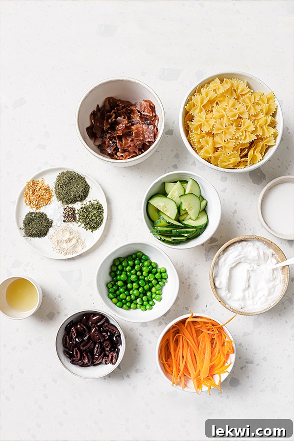 All the fresh ingredients laid out on a table, including gluten-free bow tie pasta, crispy bacon, mixed vegetables, and jars for the homemade ranch dressing.