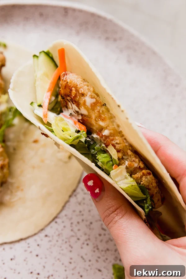 A crispy chicken snack wrap folded in a hand.