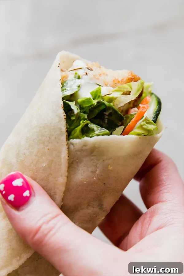 A crispy chicken snack wrap being held in a hand.