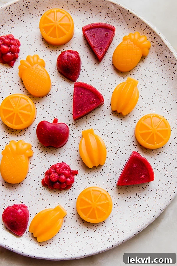 Orange and red food-shaped gummies on a plate.