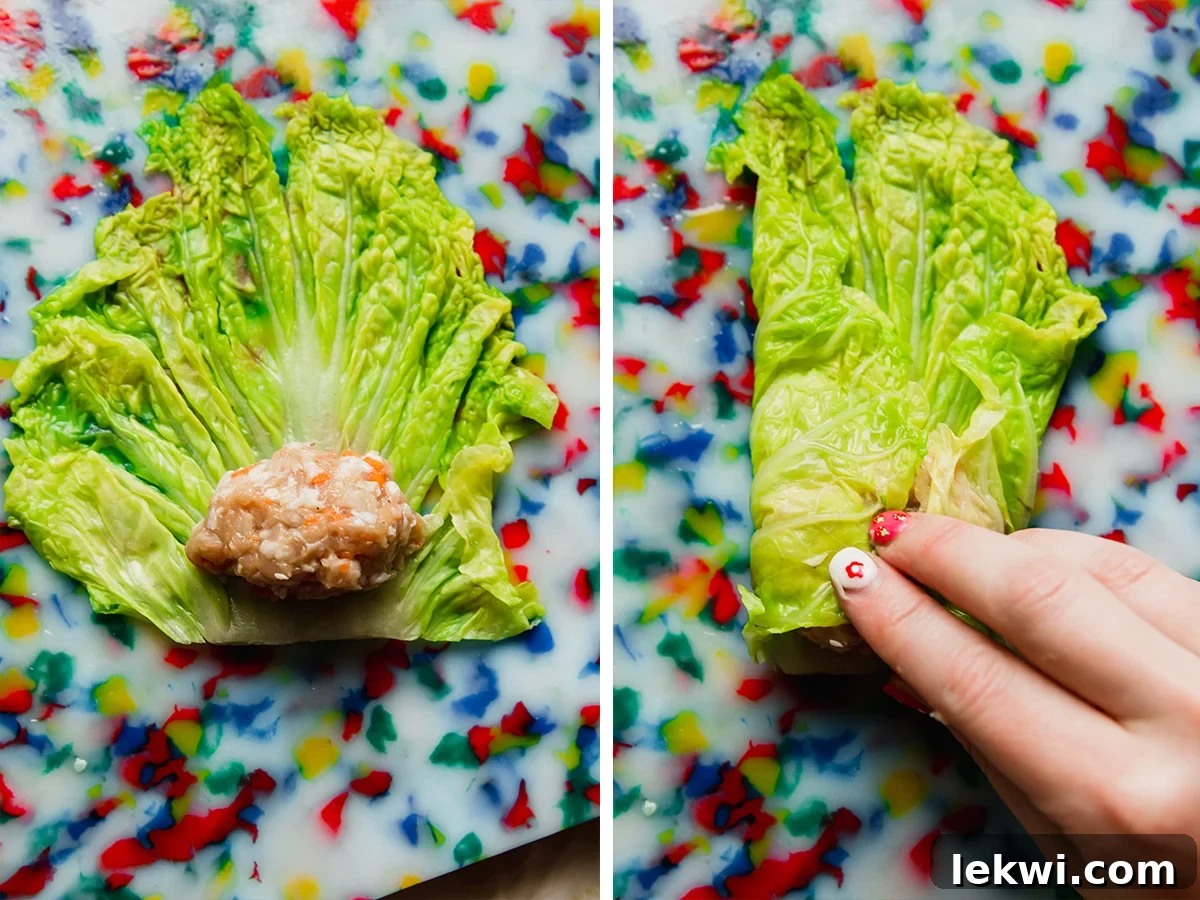 Detailed image showing the process of placing chicken filling onto a cabbage leaf and rolling it into a tight dumpling.