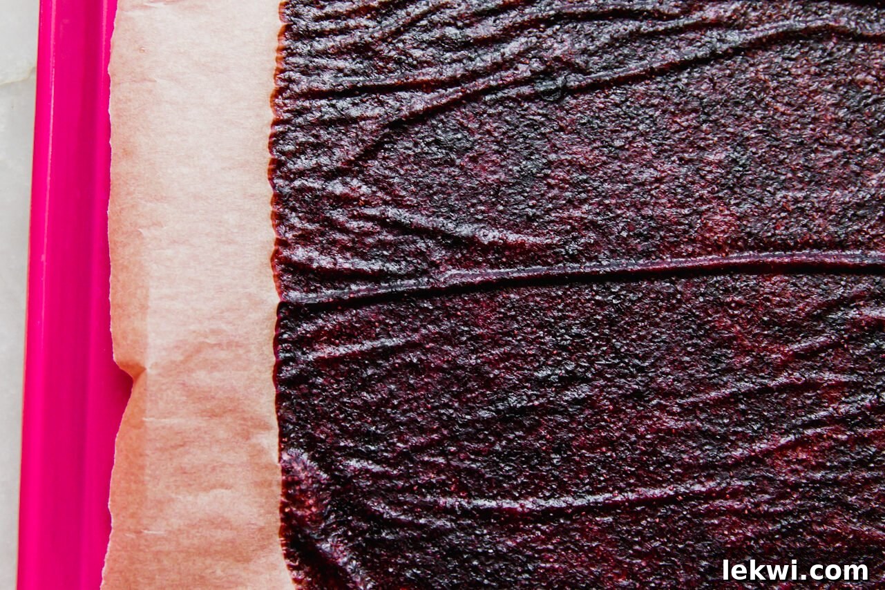 Baked fruit roll-up drying on a baking sheet in the oven.