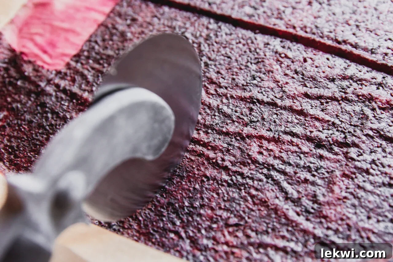 Baked fruit roll-up being sliced into strips with a pizza cutter.