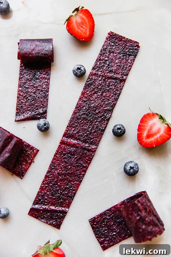 Several Homemade Fruit Roll Ups with blueberries and strawberries.
