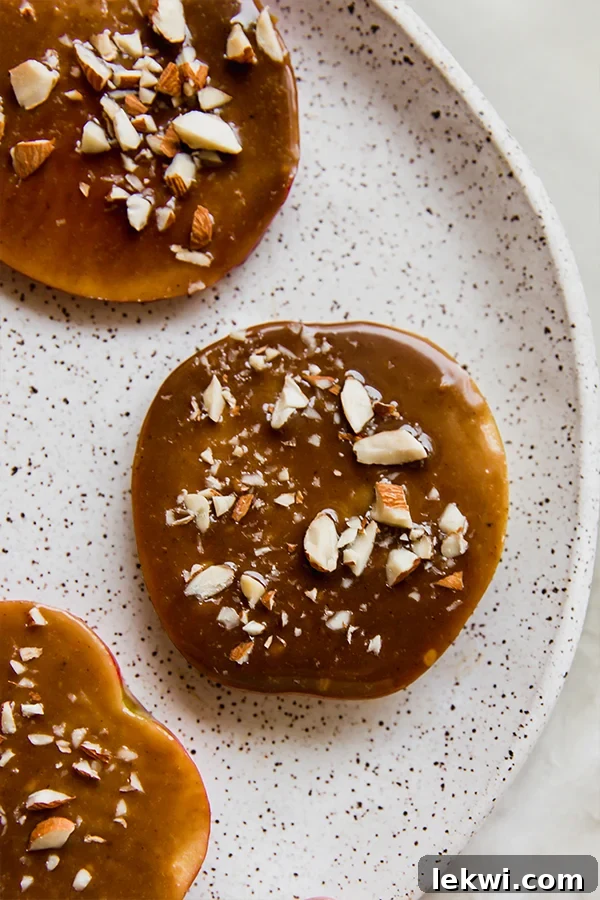 Delicious dairy-free caramel apple slices topped with crushed almonds, perfect for a fall treat.