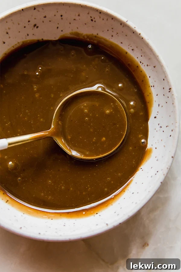 A bowl of glossy, golden coconut milk caramel ready for dipping apple slices.