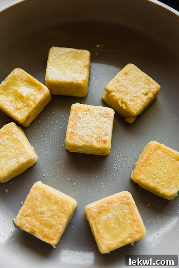 Golden brown crispy chickpea tofu cooking in a pan.