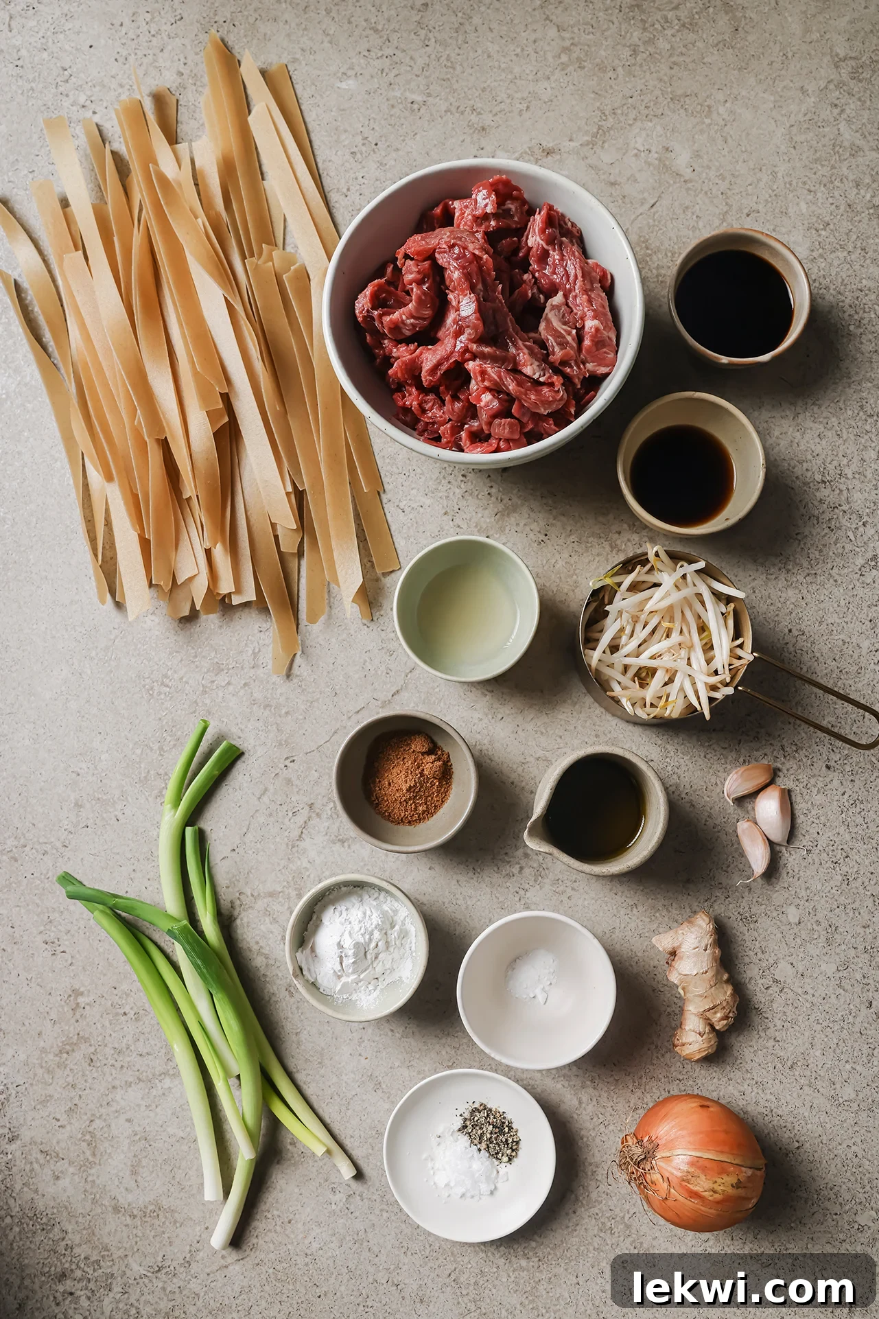 Beef chow fun ingredients laid out on a beige background.