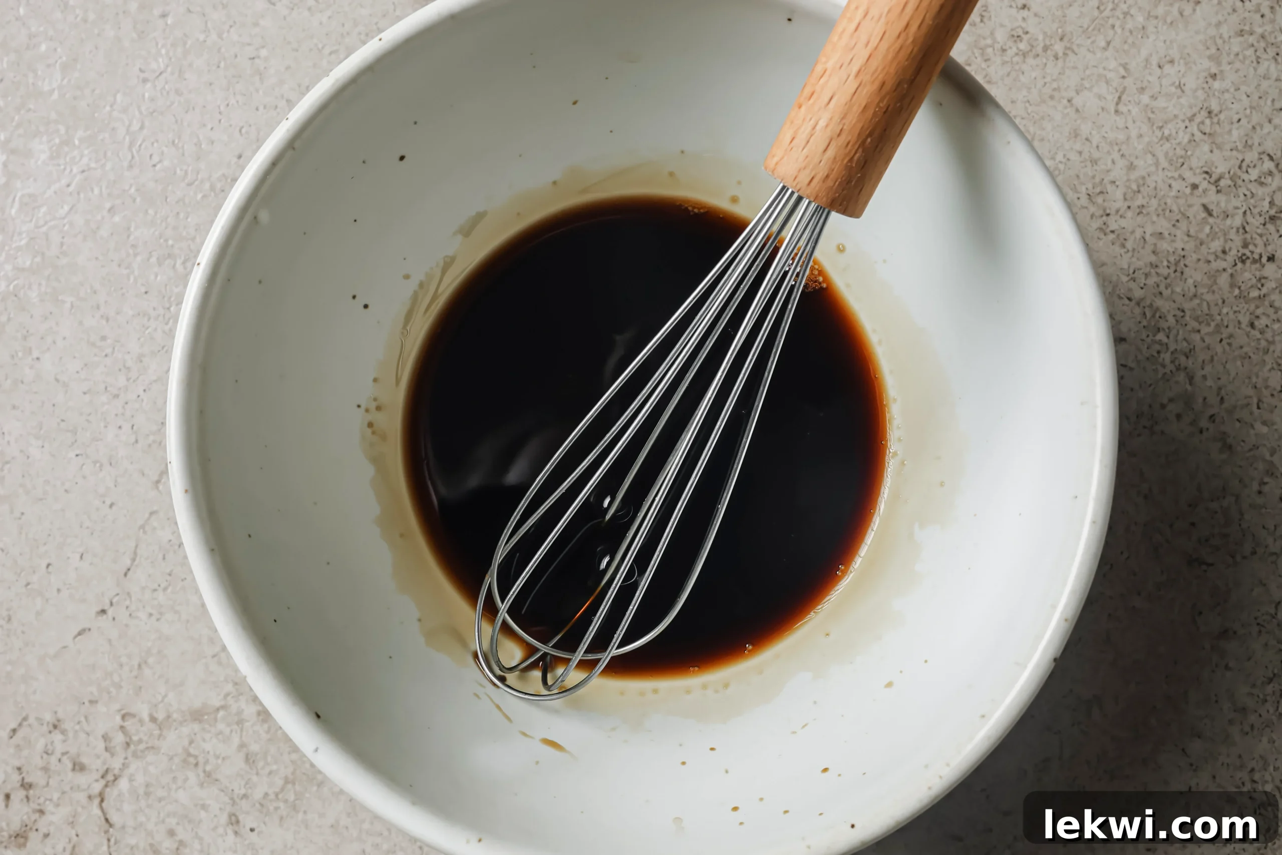 Beef chow fun sauce in a large bowl with a whisk.