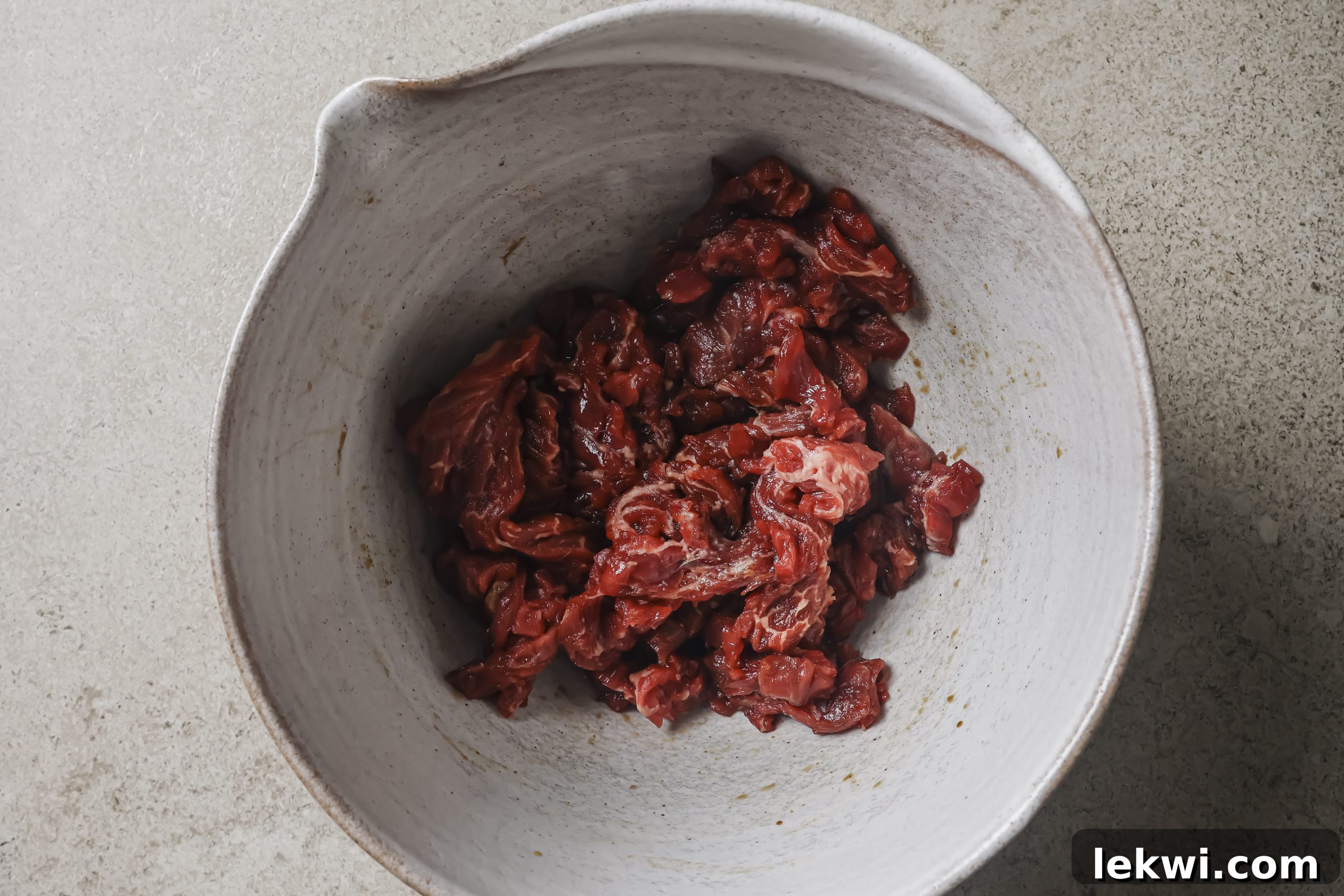 Sliced steak marinating in a bowl. 
