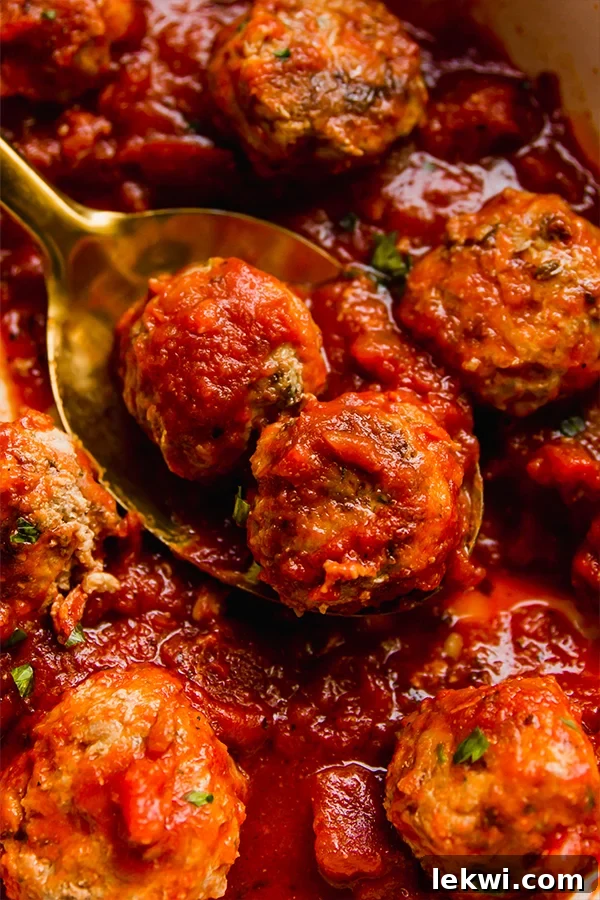 Wholesome Hidden Veggie Meatballs Gluten and Dairy Free 2 Spoon scooping a perfectly cooked hidden veggie meatball from a pot of sauce.