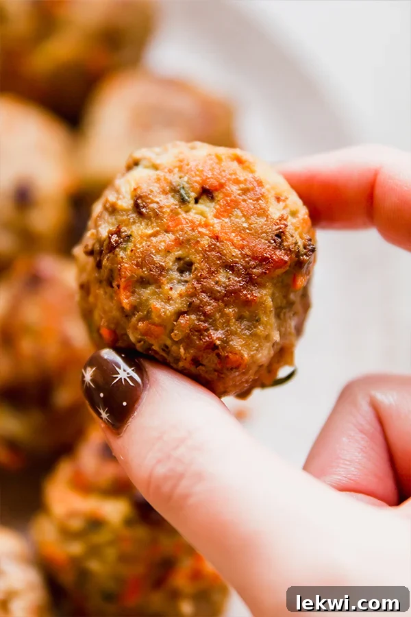 Wholesome Hidden Veggie Meatballs Gluten and Dairy Free 5 A hand holding a single, fully cooked hidden veggie meatball, showcasing its delicious texture.