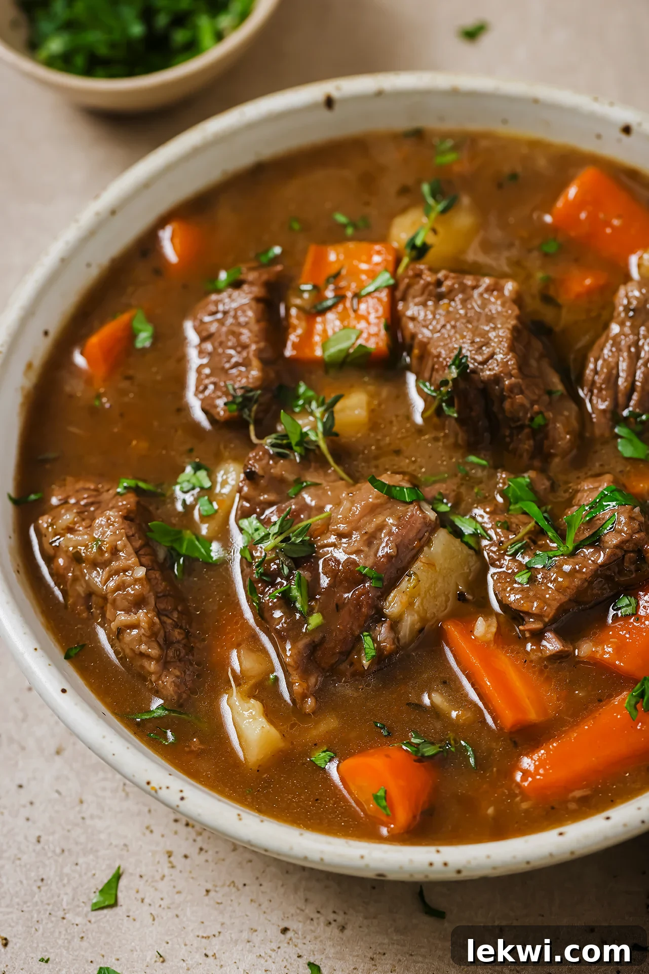 Dutch oven beef stew in a bowl topped with parsley.