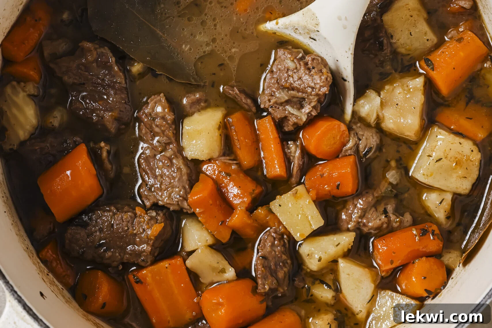 Dutch oven beef stew in a pot, with a spoon.