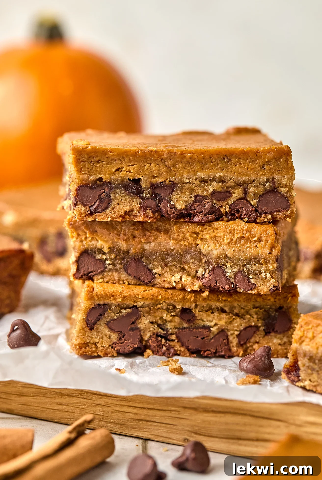 A close-up of three stacked gluten-free and dairy-free pumpkin chocolate chip cookie bars, showcasing the rich pumpkin layer and the chocolate chip-studded cookie base, ready for serving.