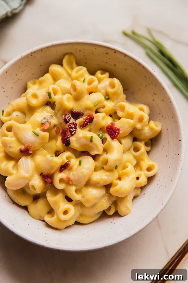 A beautifully presented bowl of creamy dairy-free pumpkin mac and cheese, garnished with fresh chives.