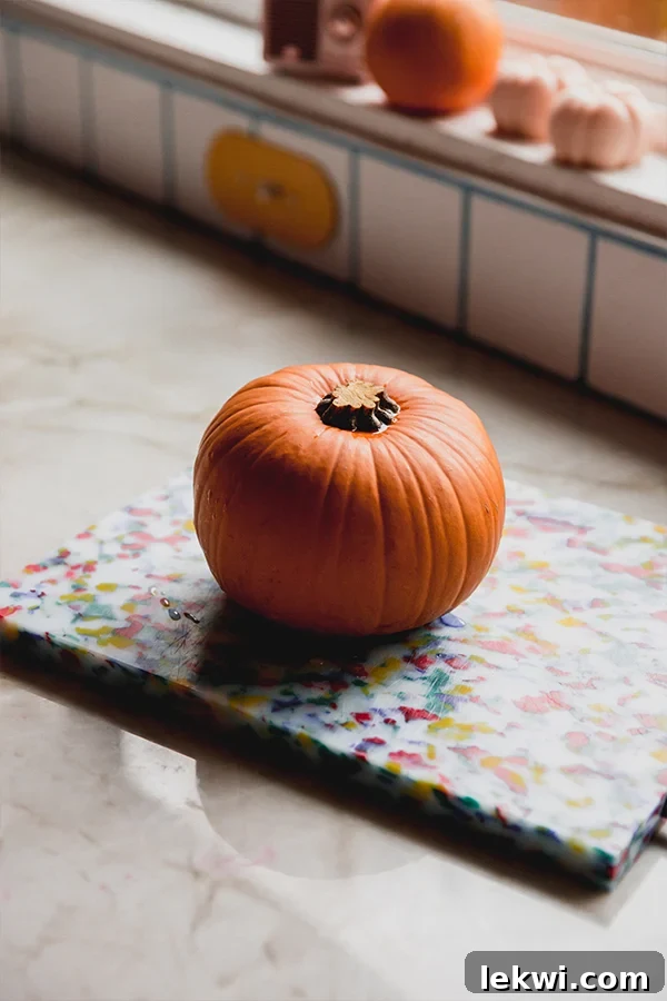 A whole sugar pumpkin sitting on a wooden cutting board, ready for preparation before roasting.