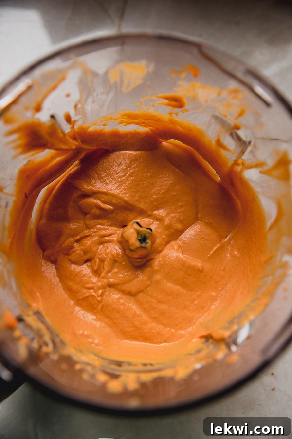 A food processor blending creamy pumpkin mixture for the dessert.