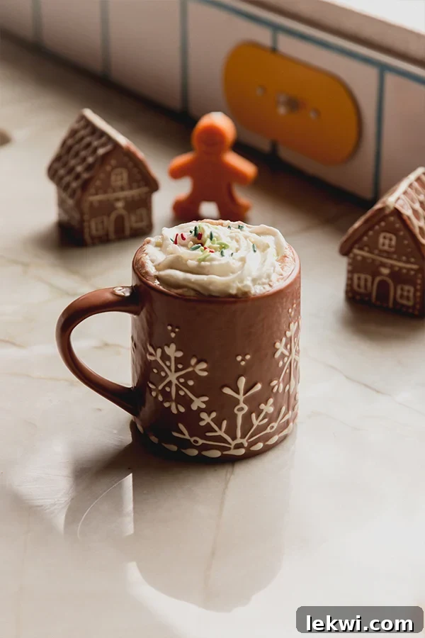 Gingerbread hot cocoa with whipped cream in a mug.
