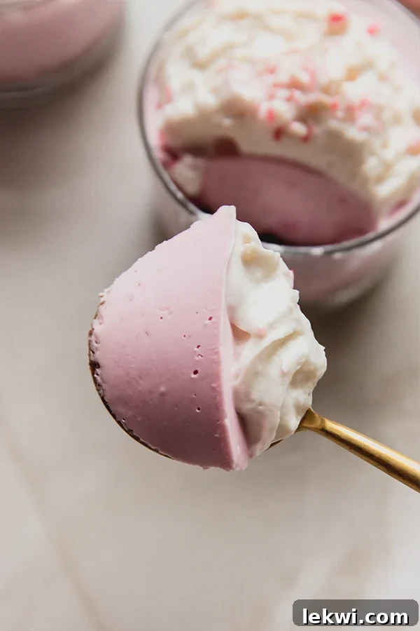 A spoon taking a perfect bite out of a mini peppermint pie cup, showing the creamy filling and crumbly crust.