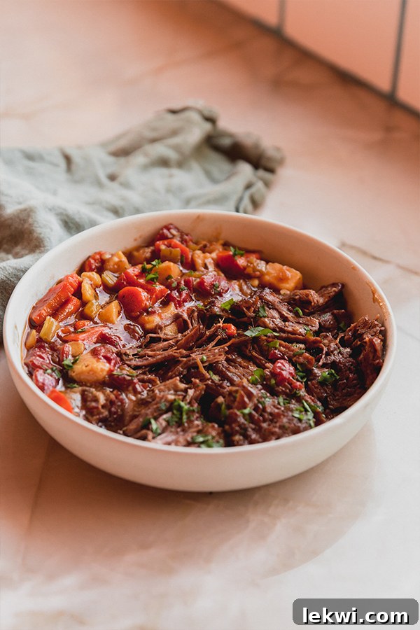 A bowl of delectable Italian pot roast, ready to be enjoyed on a rustic wooden counter, with a napkin nearby.