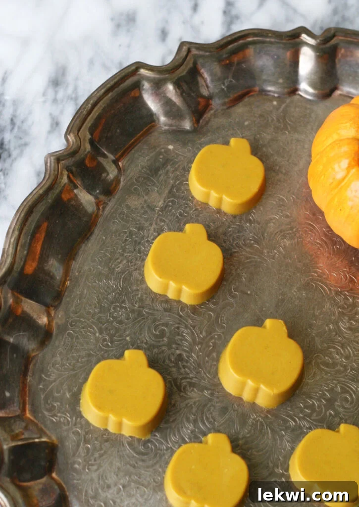 Close-up of small pumpkin-shaped turmeric gummies on a decorative plate.