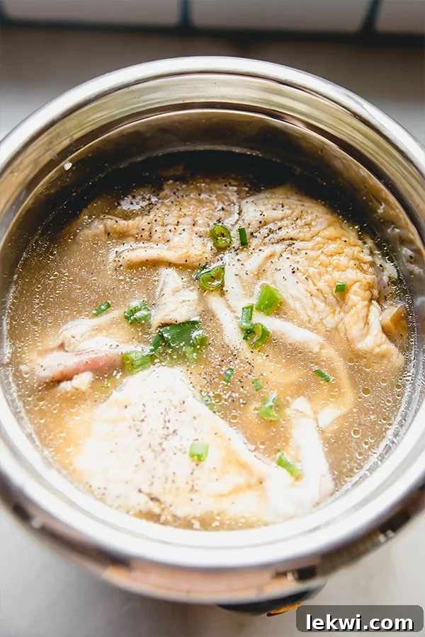 The rice cooker filled with chicken and other ingredients before cooking.