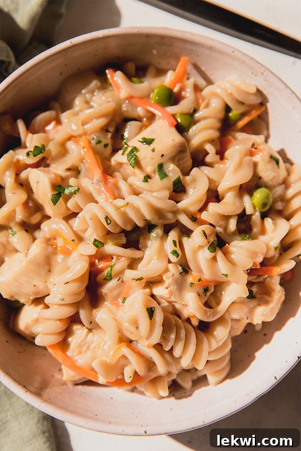 A beautifully presented bowl of creamy, hearty Chicken Pot Pie Pasta, garnished with fresh parsley, inviting you to dig in.