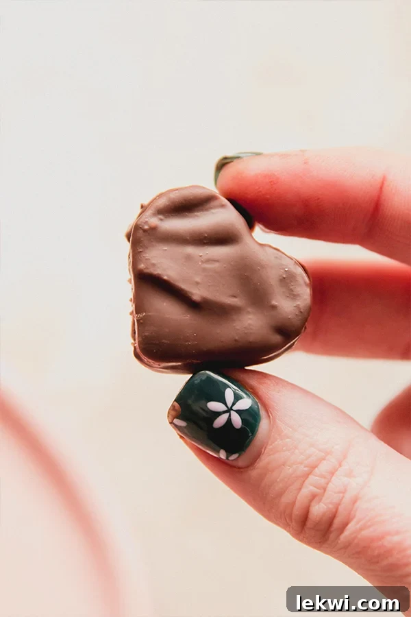 Person holding a heart-shaped chocolate gummy.