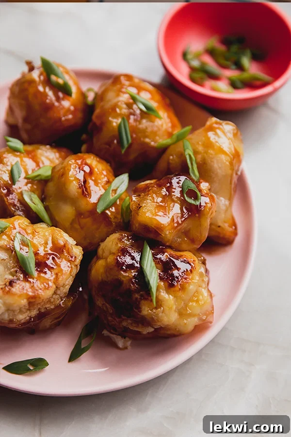 Plate of teriyaki crispy cauliflower wings, garnished with green onions and sesame seeds.