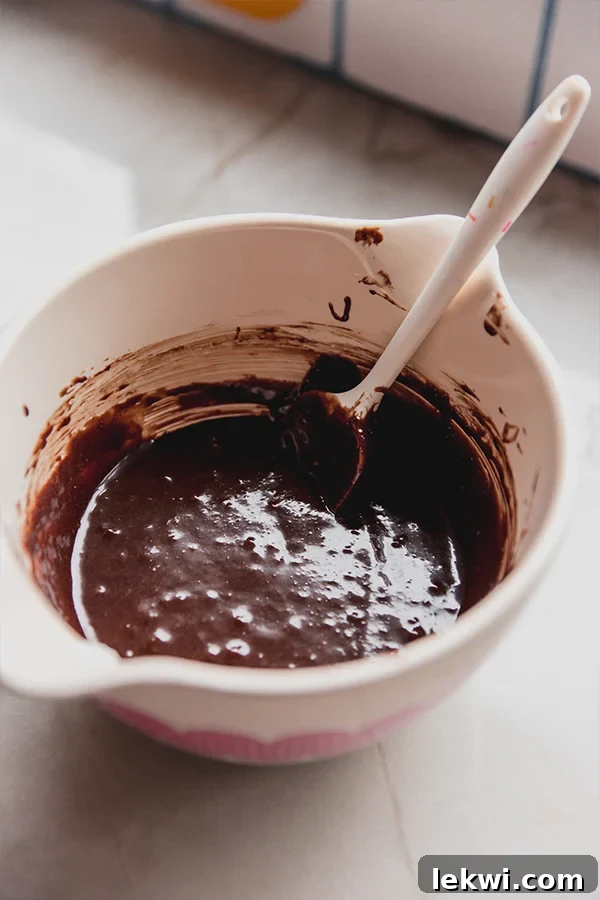 A mixing bowl filled with smooth, dark chocolate batter for lava cakes, ready for baking.