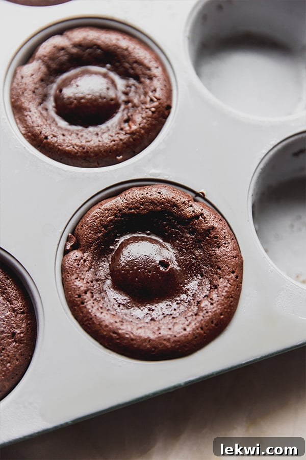 A baking pan filled with six perfectly baked chocolate lava cakes, cooling slightly before serving.