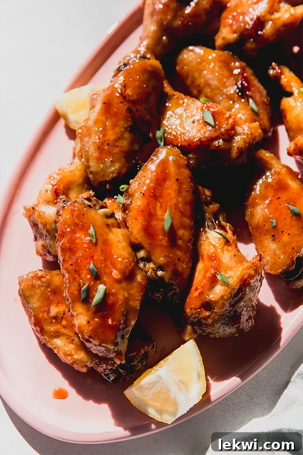 Crispy lemon garlic chicken wings arranged elegantly on a pink serving plate, garnished with fresh herbs, showcasing their golden-brown perfection.