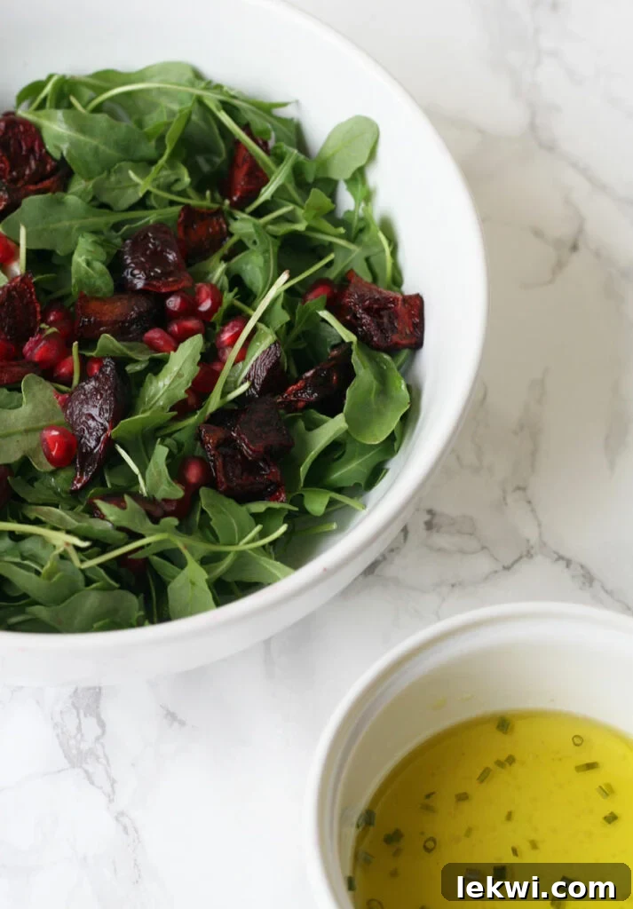 Jeweled Fall Pomegranate Beet Salad AIP Paleo Vegan Friendly 2 Vibrant Pomegranate Beet Salad in a white bowl, showcasing beautifully roasted beets, fresh arugula, and glistening pomegranate seeds. A perfect healthy fall salad recipe.