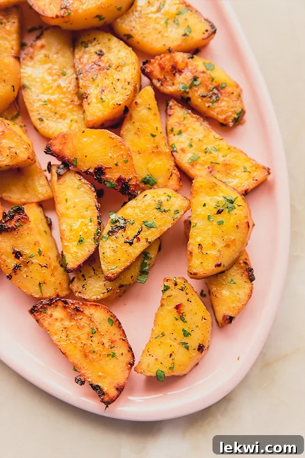 Greek lemon sweet potatoes on a pink plate, garnished with fresh parsley.