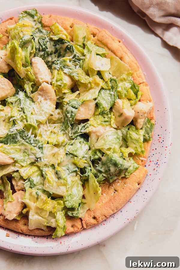 Chicken Caesar salad pizza on a round plate.