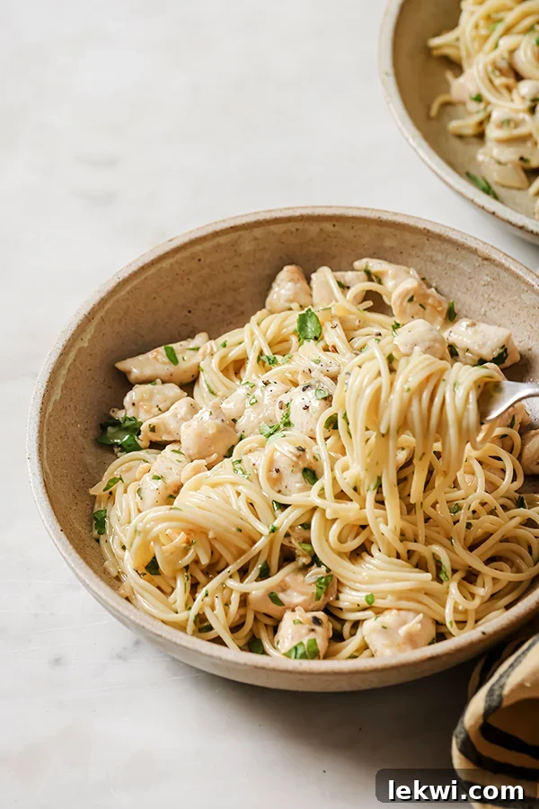Fork lifting some chicken scampi from a bowl.