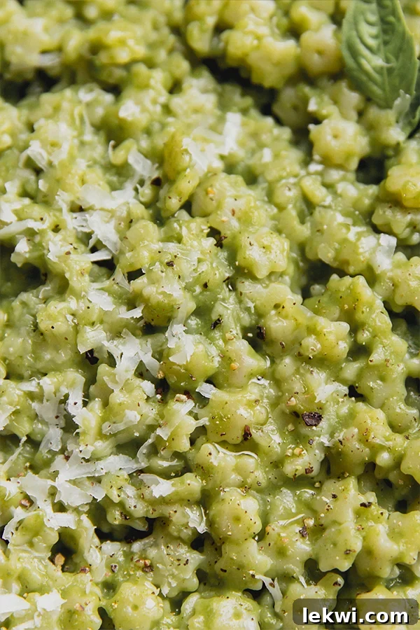 A close-up shot of basil pesto stelline, showing the star-shaped pasta coated in vibrant green pesto, garnished with fresh basil leaves.