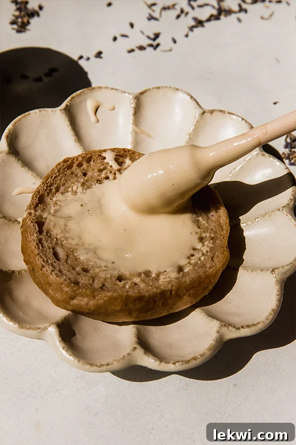 A utensil spreading homemade lavender whipped honey on a piece of bread.