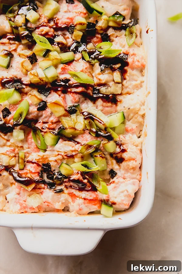 Salmon sushi bake in a baking dish topped with cucumber, green onion and eel sauce.