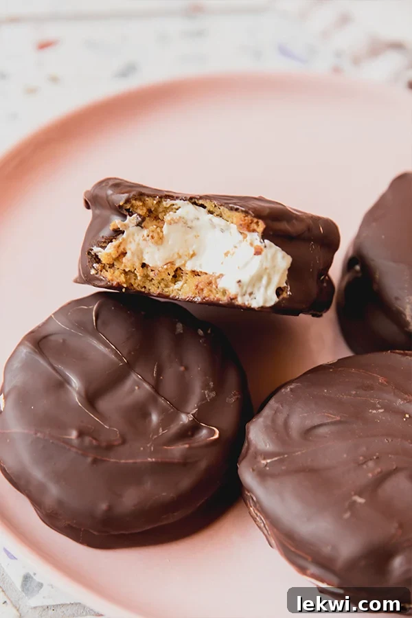 Gluten free moon pies on a pink plate with a bite taken out of one to show the cookies sandwiching the marshmallow cream.