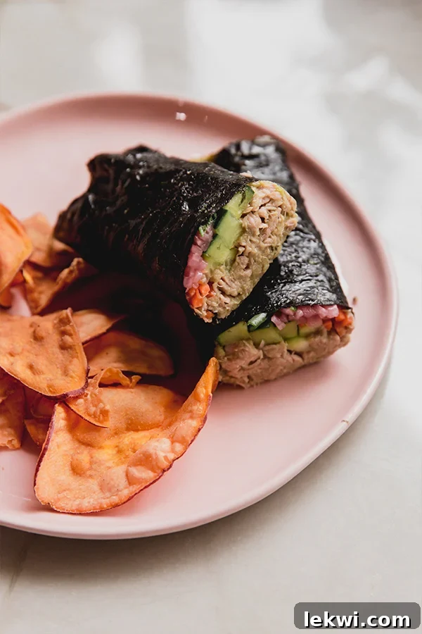 A thoughtfully presented plate featuring a tuna seaweed wrap, neatly cut in half, alongside a handful of crispy chips, ready to be enjoyed as a satisfying and healthy meal.