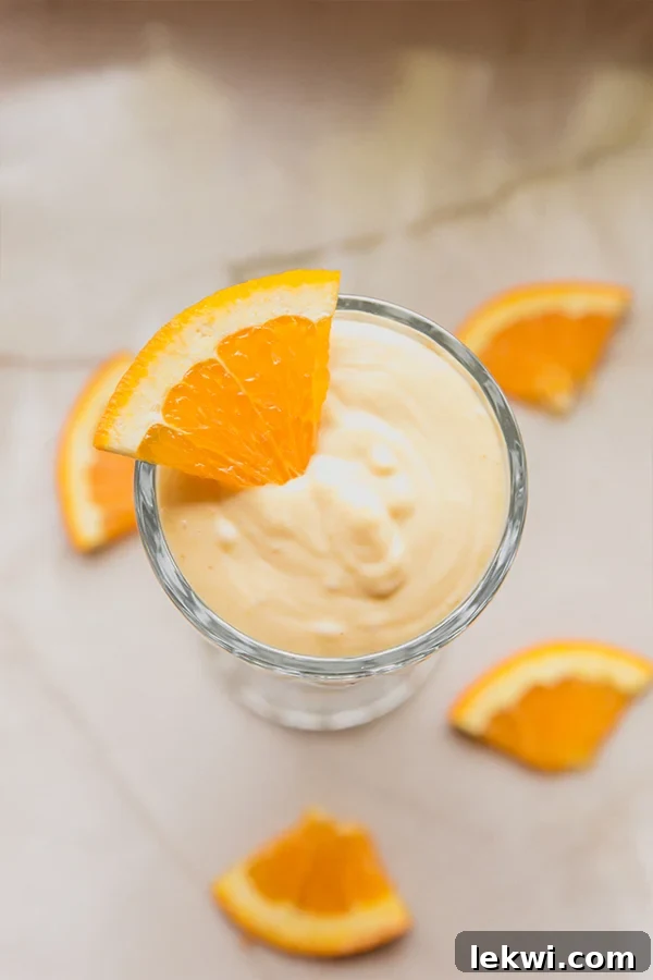 Overhead view of a finished dairy-free Creamsicle Frosty in a milkshake cup with an orange slice on top.