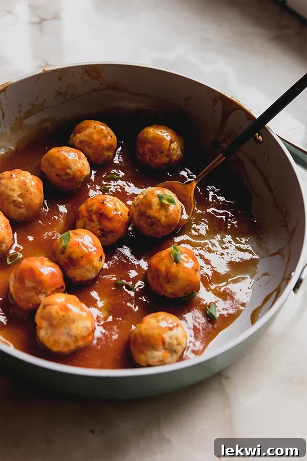 A pan filled with the freshly cooked sweet & sour chicken meatballs, glistening with sauce.