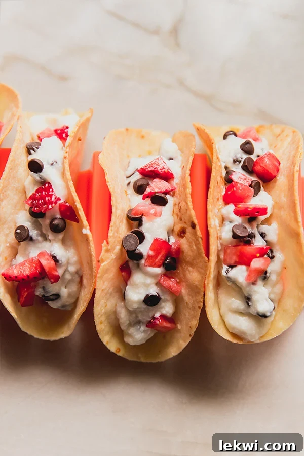 Cannoli tacos topped with strawberries and chocolate chips in a taco holder.