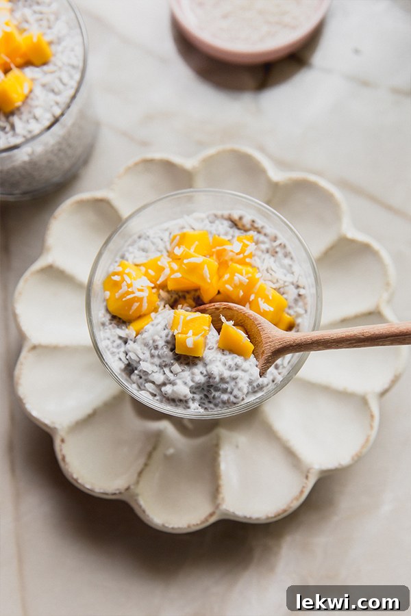 A spoon taking a satisfying bite out of a cup of mango sticky rice chia pudding, revealing its creamy layers and delicious pieces of mango.