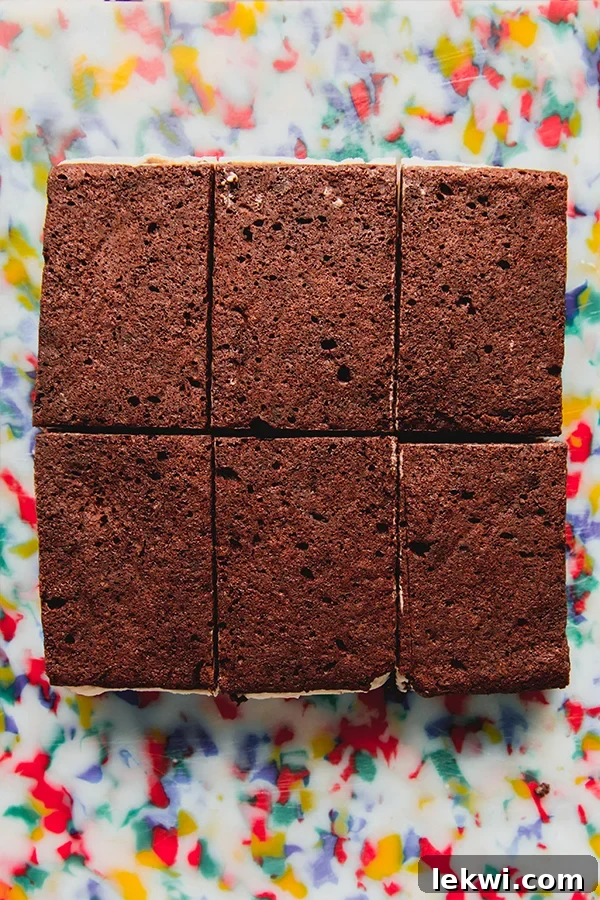 Six gluten free brownie ice cream sandwiches on a colorful cutting board.