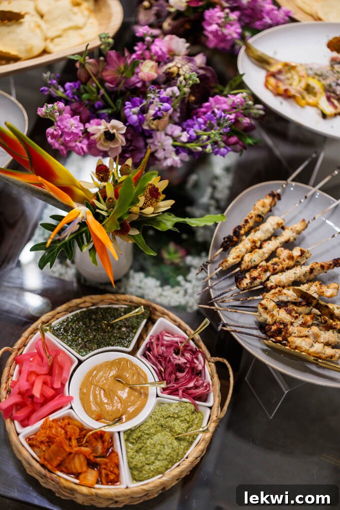 A lavish spread of chicken skewers and various fresh toppings for the chicken, beautifully arranged with floral accents, ready for an elegant dinner.