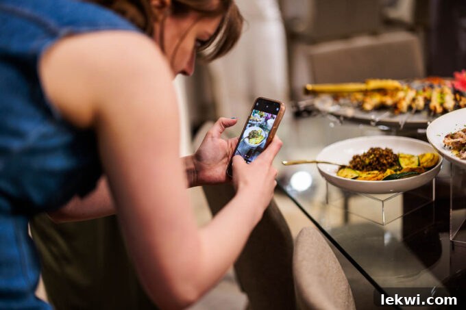 A food blogger meticulously capturing a photo of the artfully presented dinner spread with an iPhone, highlighting the dedication to content creation and food photography.